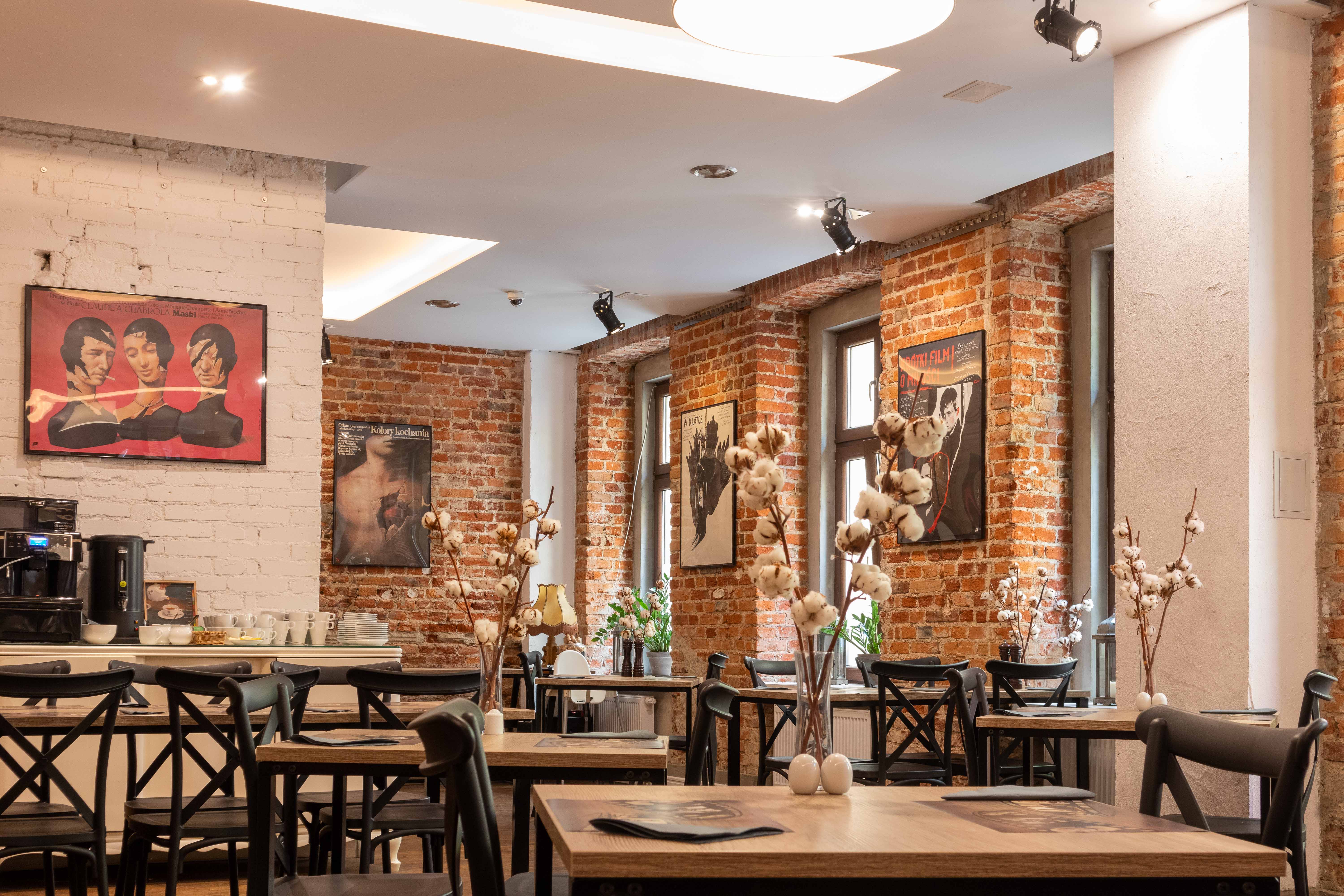 Stare Kino Cinema Residence Łódź: the Restaurant view with some tables and chairs, pictures on the brick walls and flowers on the tables