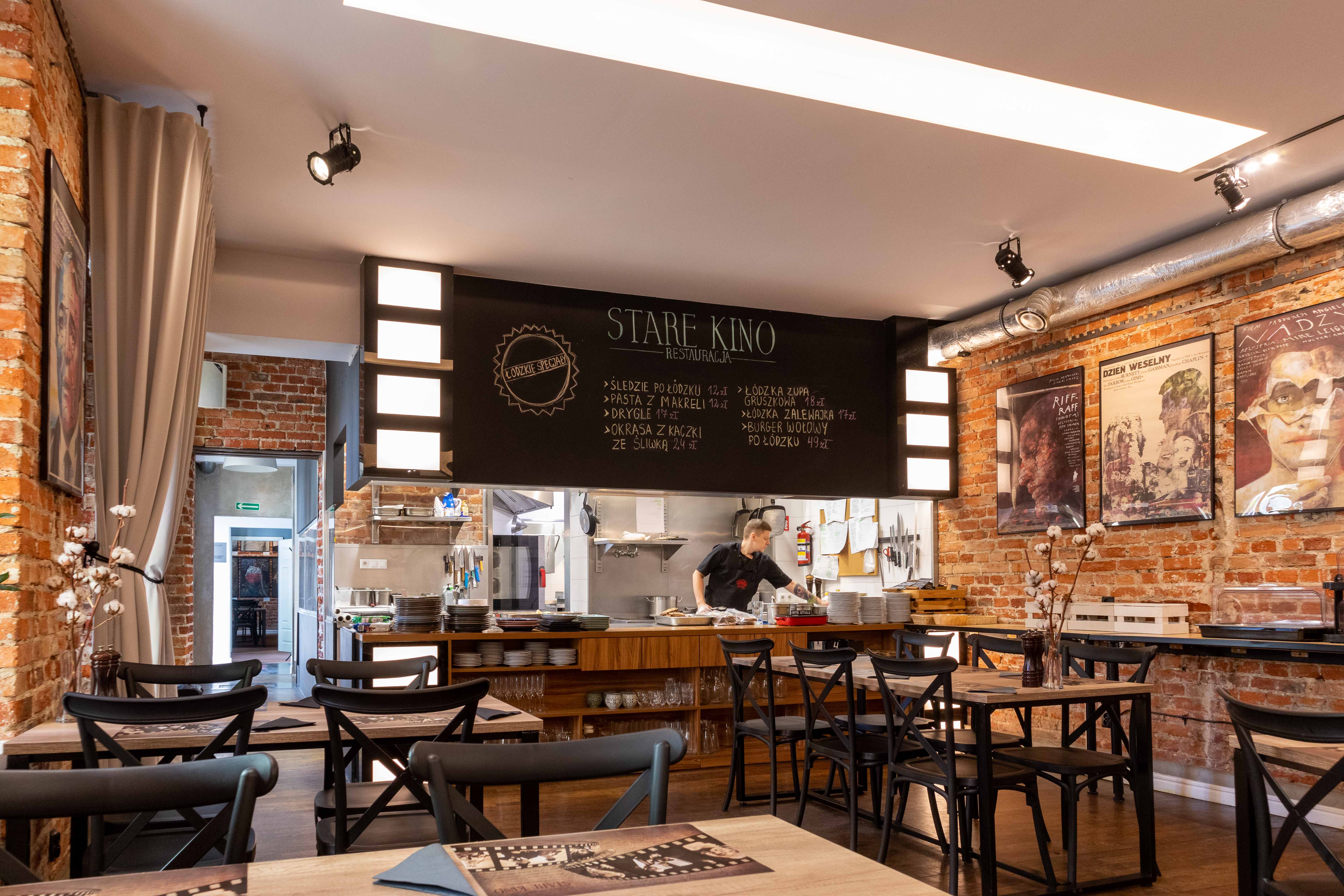 Stare Kino Cinema Residence Łódź: the Restaurant view with the tables and chairs and the cook at the back