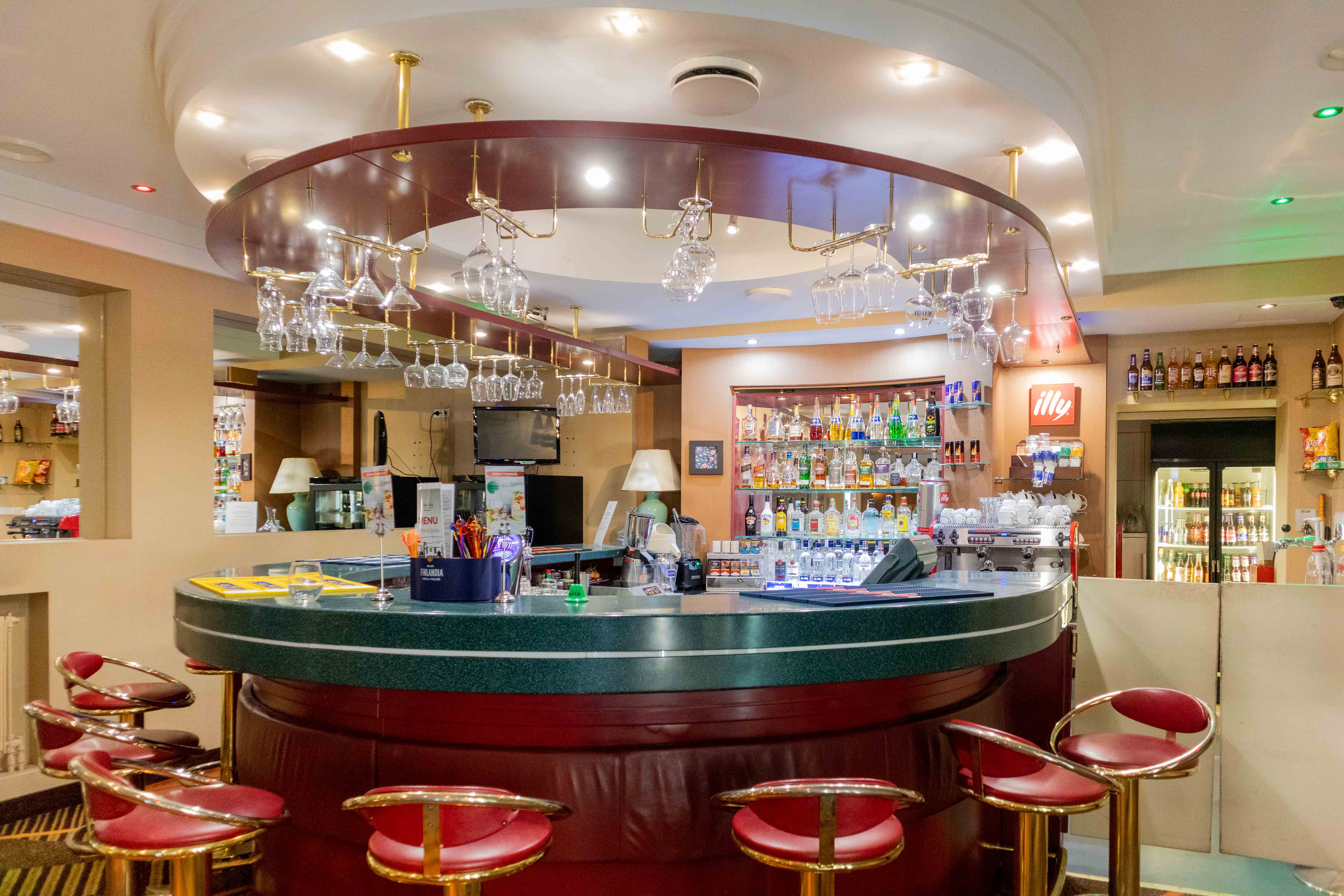 Hotel Boss Warszawa: bar side view with the bar chairs around the bar, hanging glasses and alcohol bottles at the back